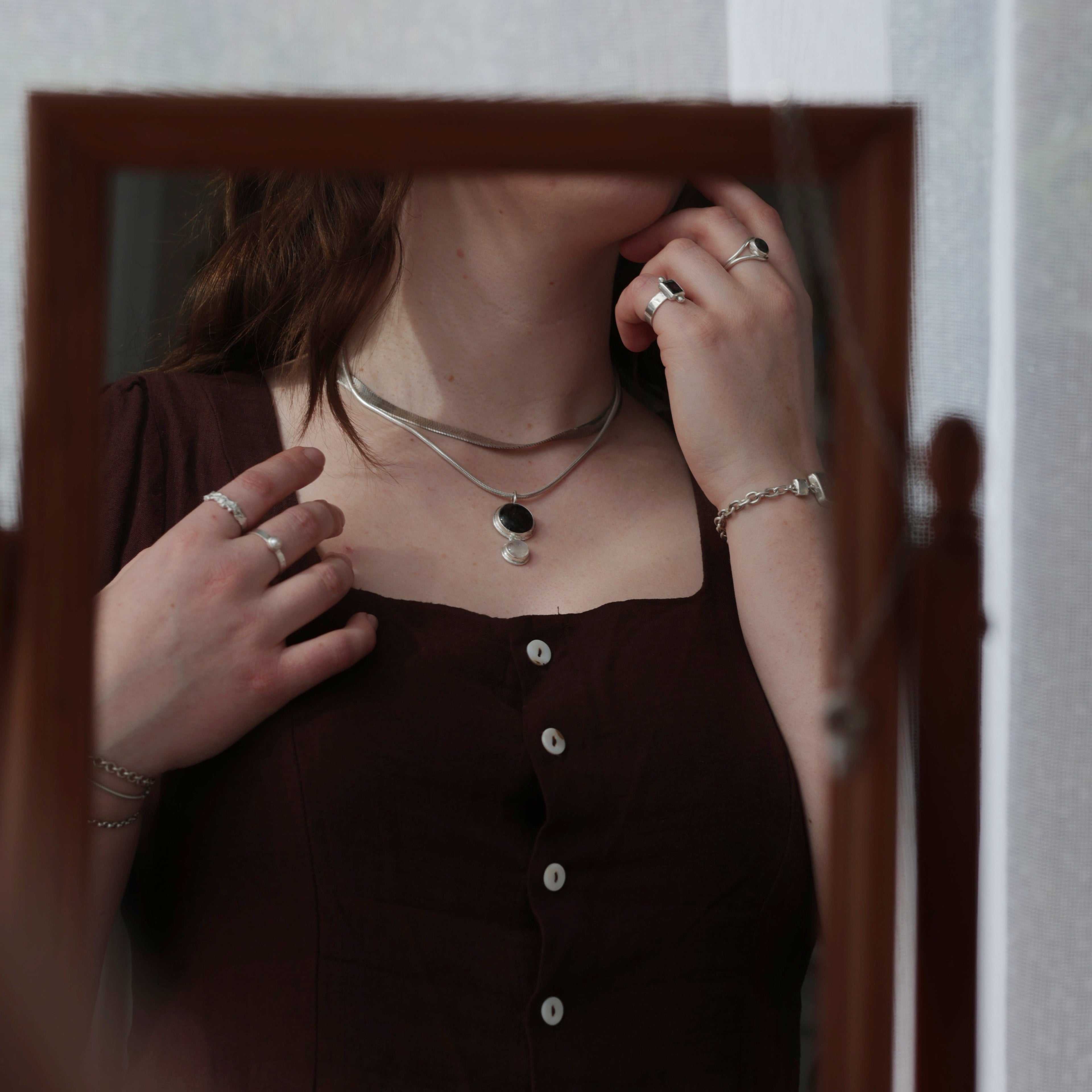 Sterling silver and gemstone jewellery being worn and shown in reflection of wooden mirror
