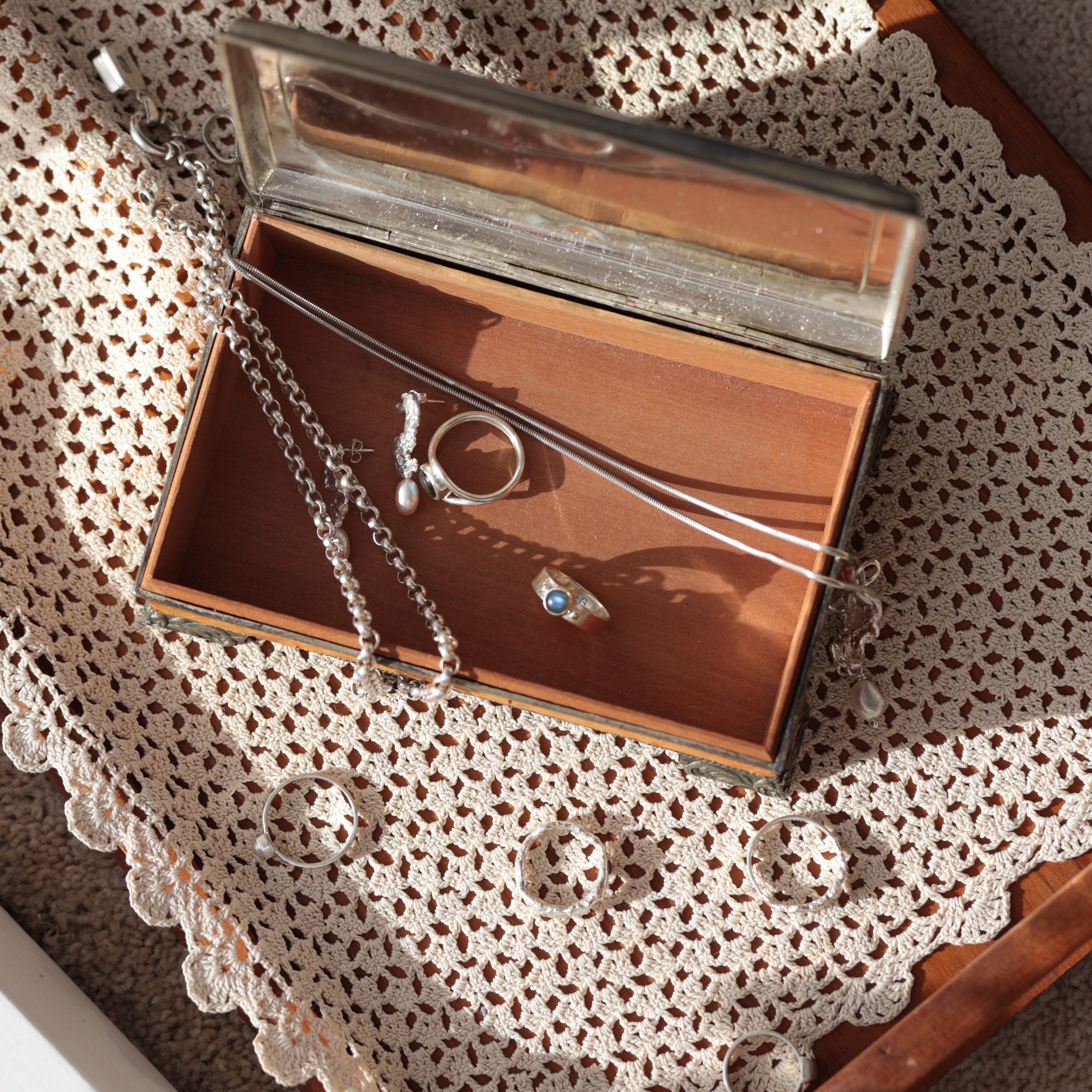 Sterling silver and gemstone jewellery flat lay on wooden jewellery box and cream lace