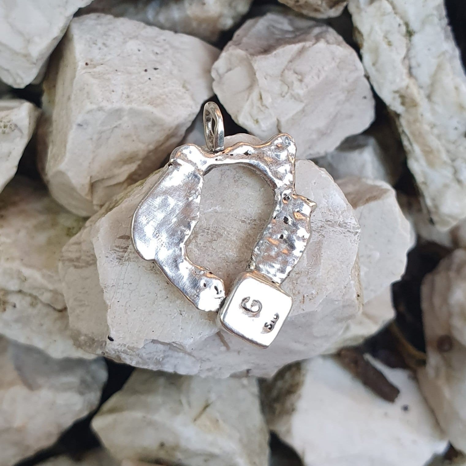 The back of an organic silver ring pendant on rocks | Made with Grace | handmade jewellery nz