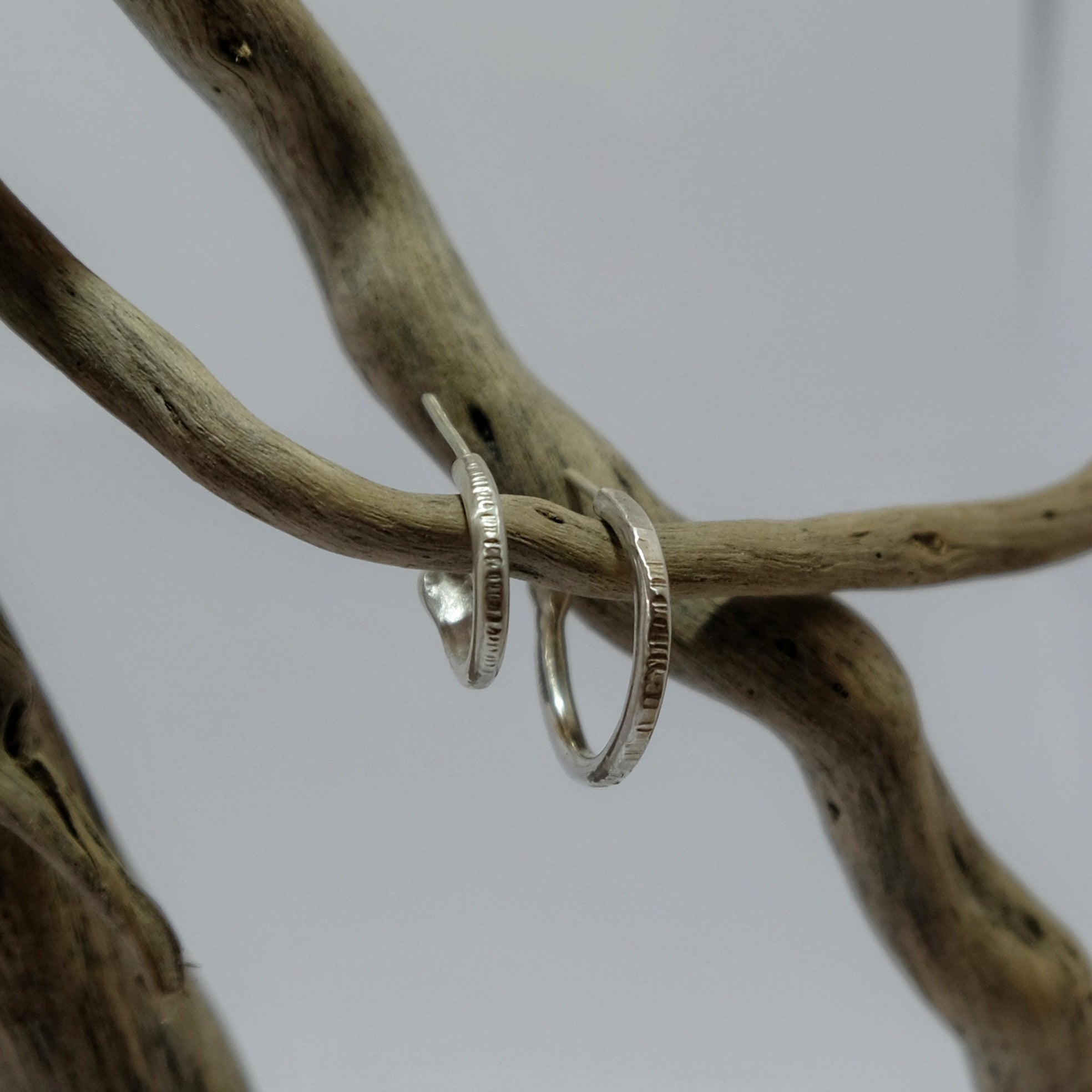 Textured silver hoop earrings hanging on driftwood | Made with Grace | handmade jewellery nz