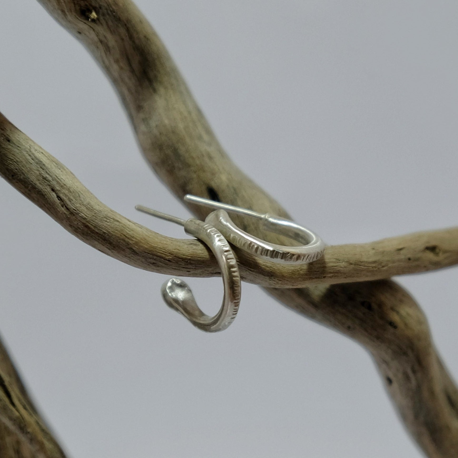 Textured silver hoop earrings lying on driftwood | Made with Grace | handmade jewellery nz